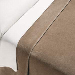 Soft velvet blanket in dark nude on a bed