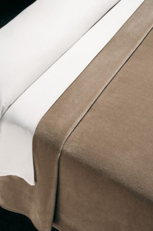 Soft velvet blanket in dark nude on a bed