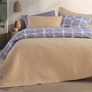 Modern bedroom featuring a beige quilted bedspread layered with geometric-patterned bedding in soft lavender and cream tones, creating a warm and contemporary look.